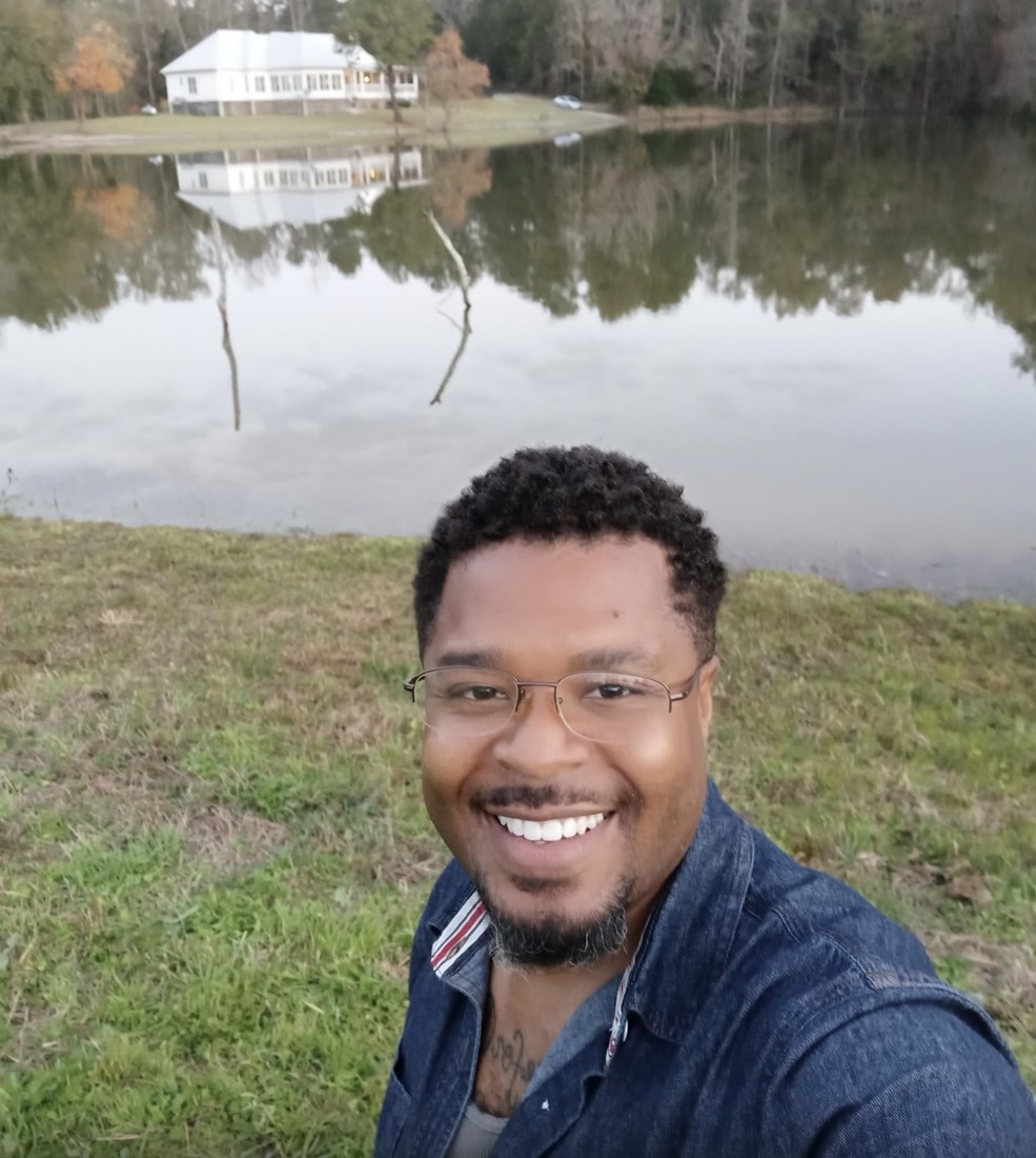Robert L. Thomas II, founder of Aaron Services LLC, smiling outdoors by a lake